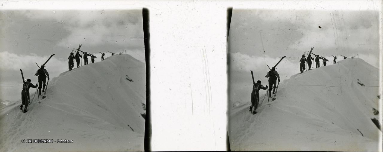 Lunga fila di concorrenti con gli sci a spalla verso il Madonnino