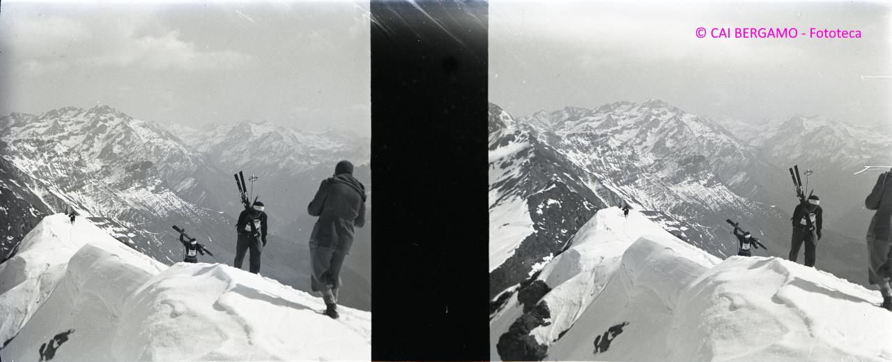 Concorrenti con gli sci a spalla verso il Madonnino e sullo sfondo la Valbondione