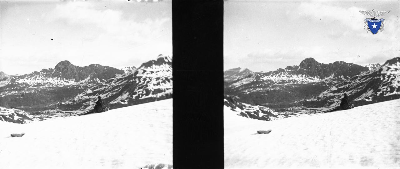 Sguardo sul Pizzo del Becco sullo sfondo dal passo di Mezzeno di sciatore comodamente seduto sulla neve