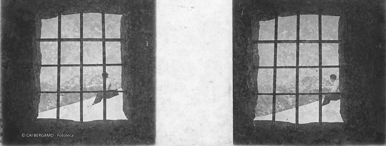 Vista dall'inferriata con skiatore seduto e le cime della valle in lontananza