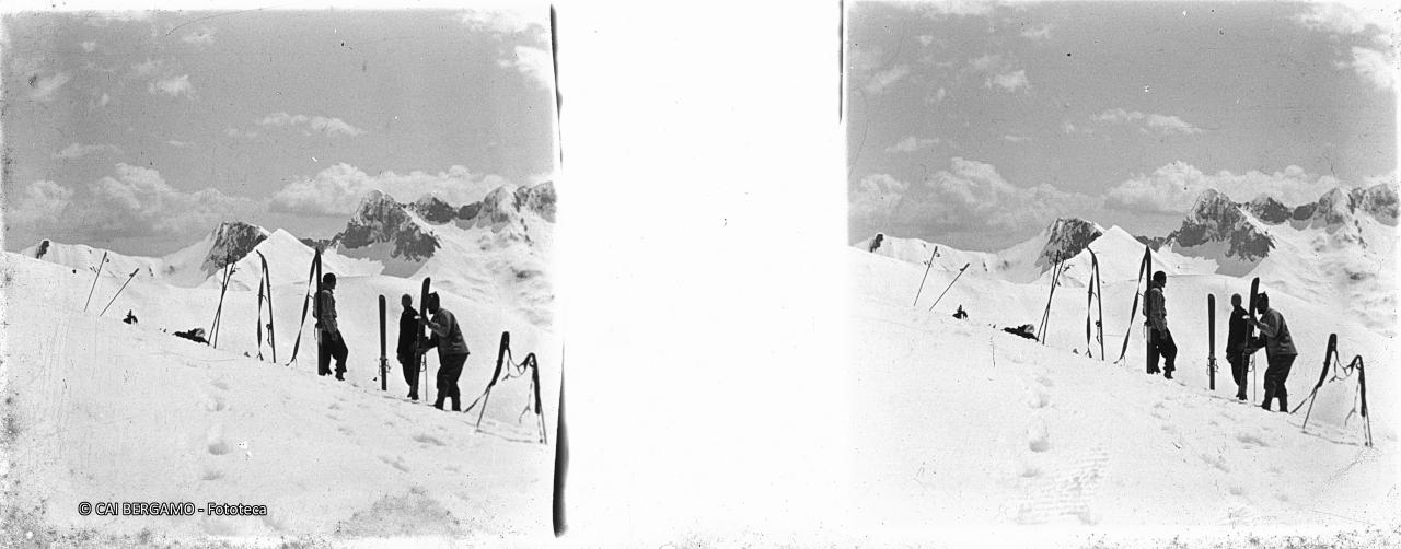 Sciatori con sci a riposo e vista da sinistra: bocchetta NE del Barbarossa, il Barbarossa ed il Pizzo di Petto