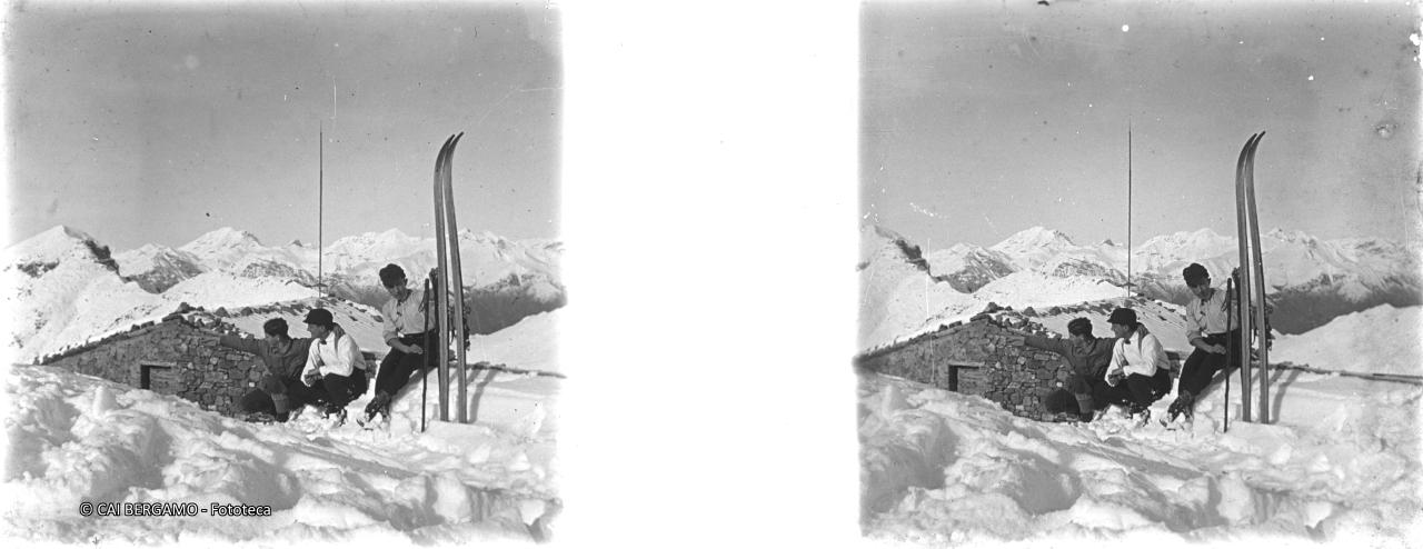 Ragazzi seduti sulla neve accanto a baita