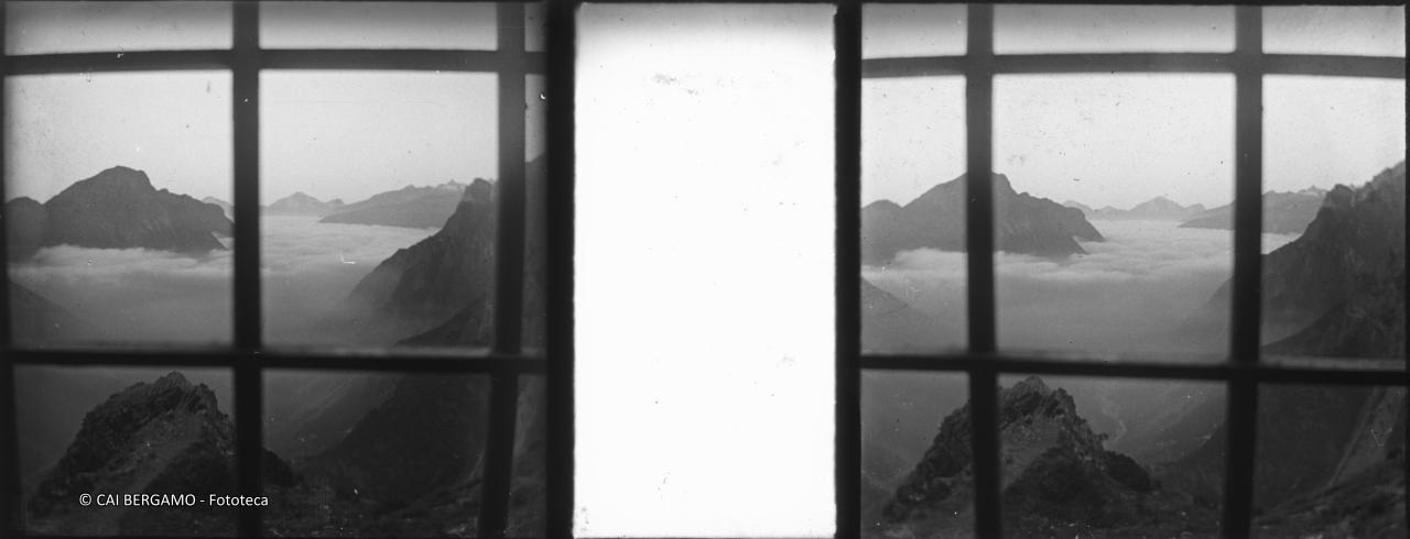 Vista dalla finestra del vecchio rifugio Curò sulla valle immersa nella nebbia con il Vigna Soliva e sullo sfondo l'Arera