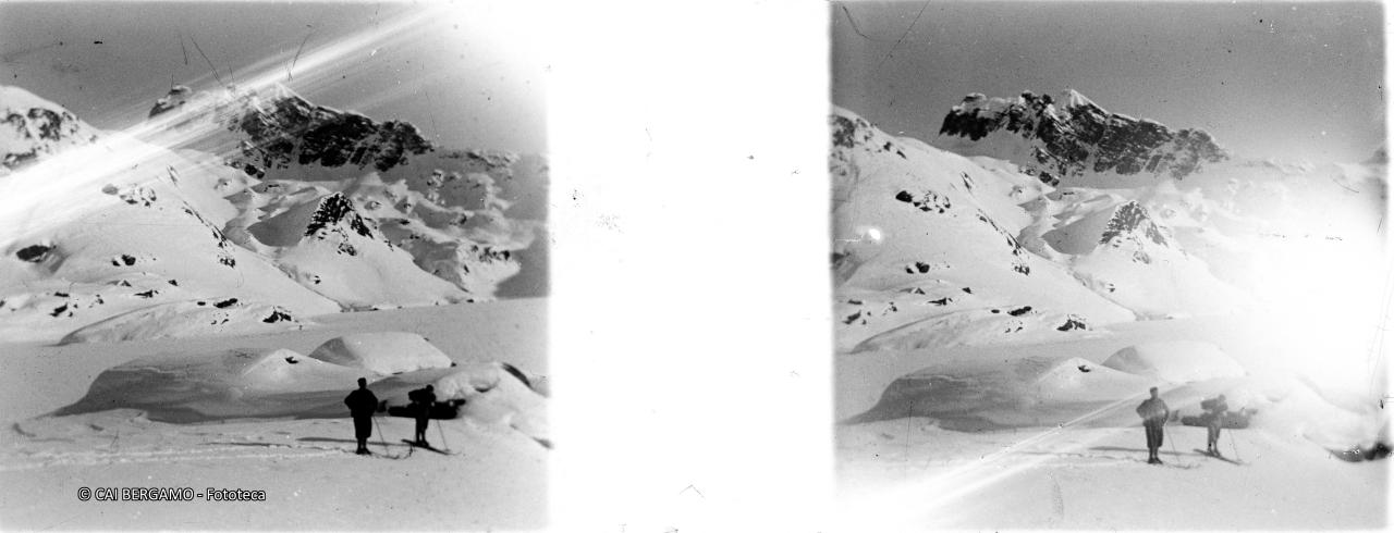 Skiatori ai bordi del lago ben innevato sotto la sguardo del monte Corte
