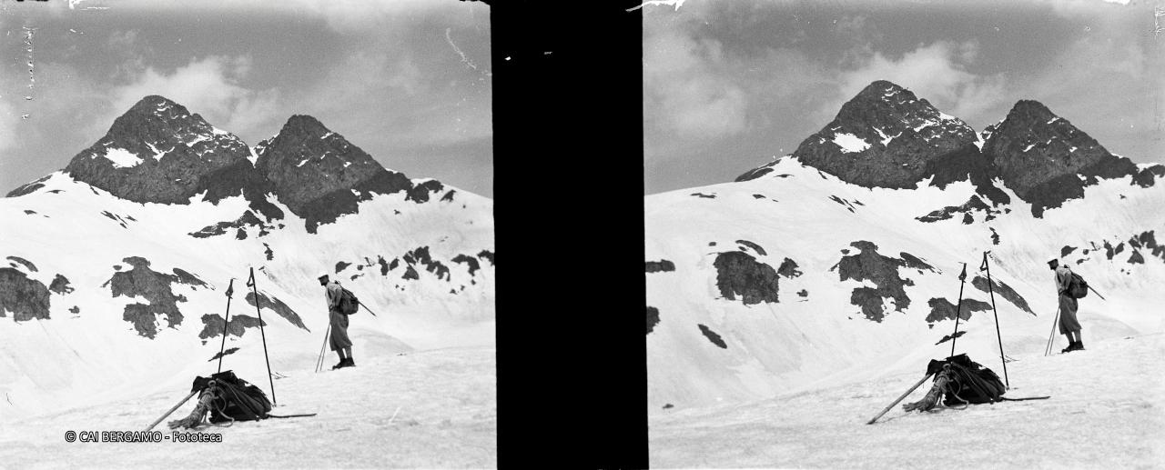 Skiatore sotto lo sguardo dei 2 Diavoli con zaino corda e  bastoncini in primo piano
