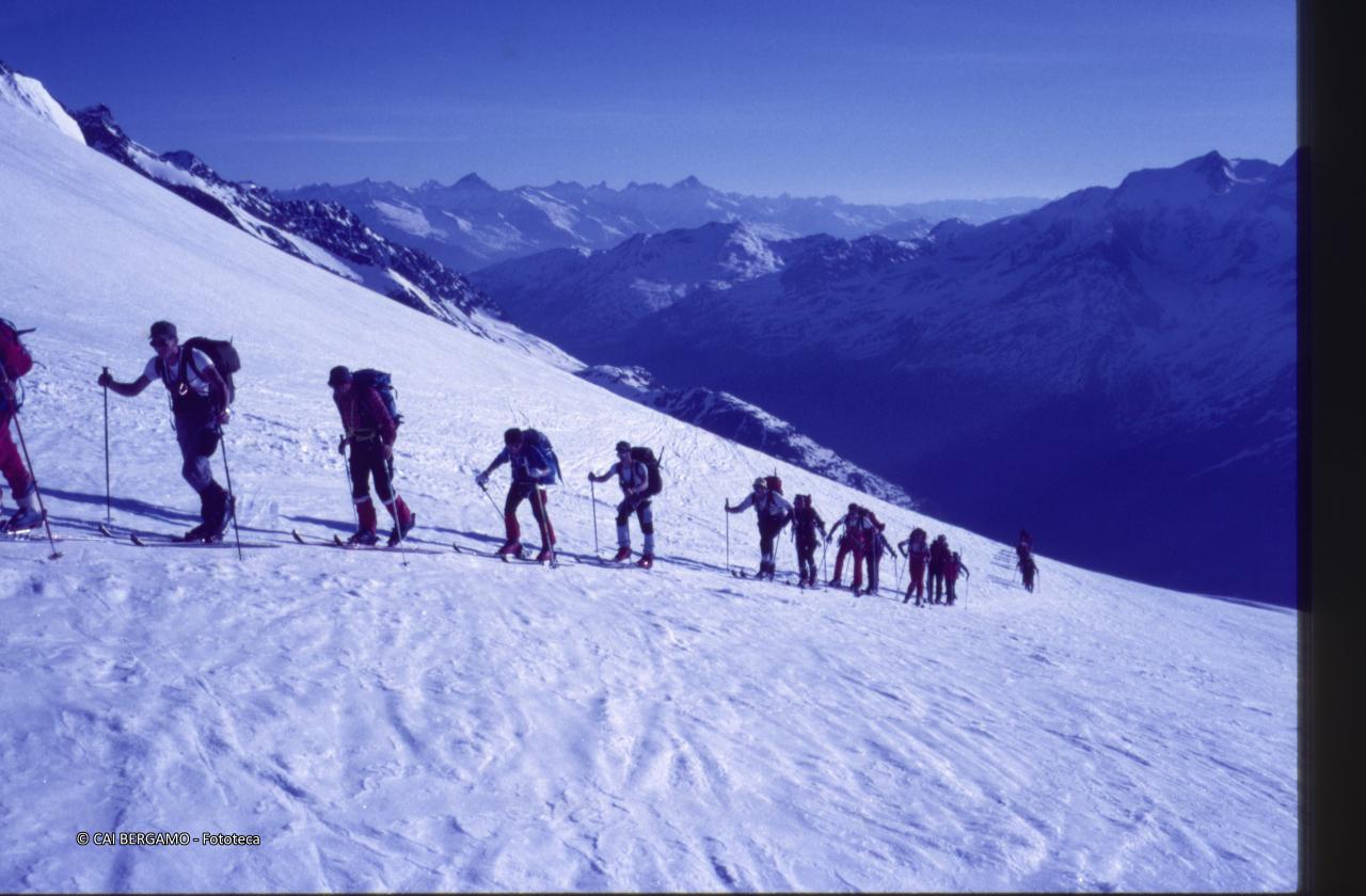 Scialpinisti in fila indiana con vista sulle alpi del Canton Vallese