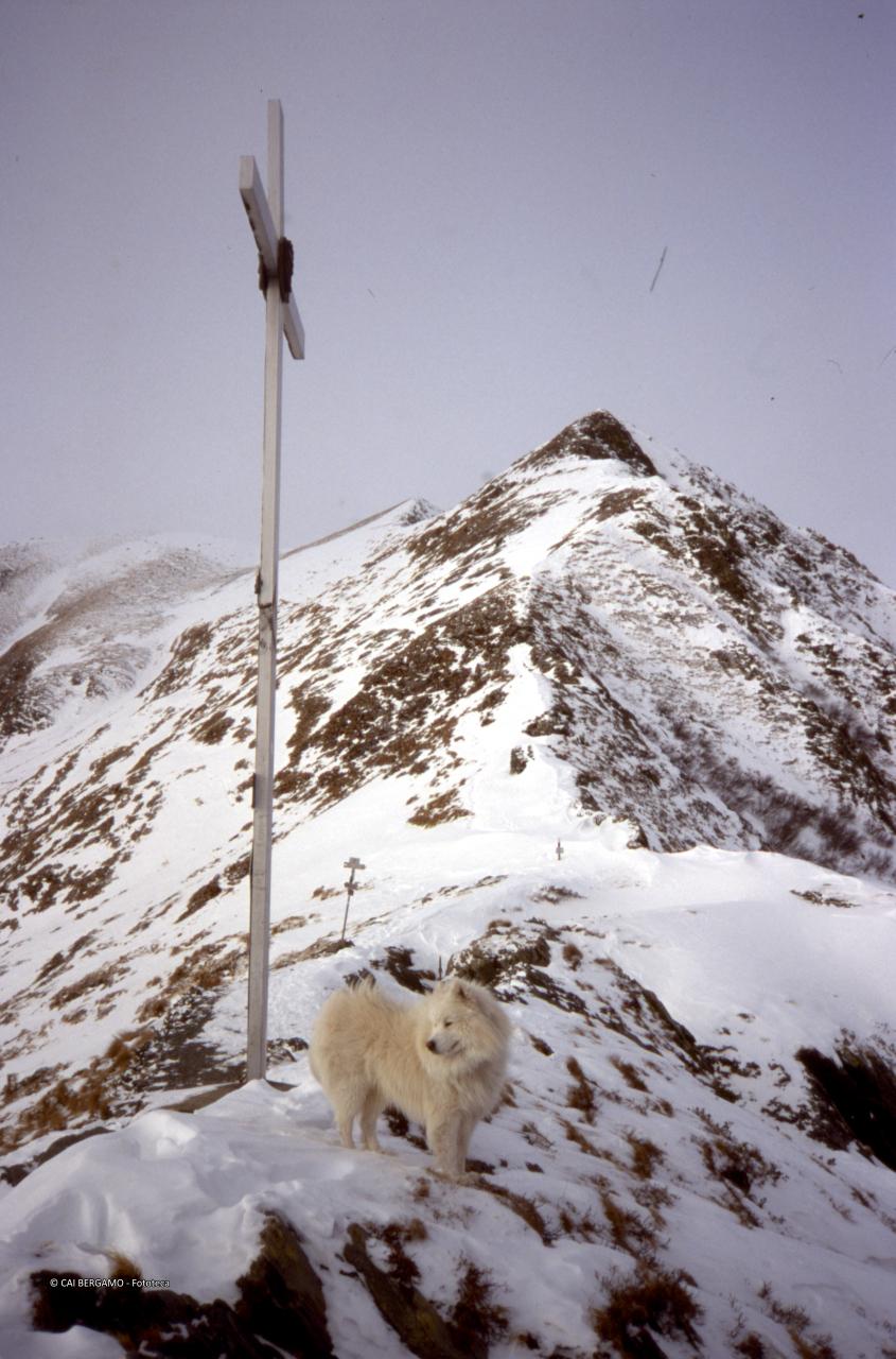 Sotto macchie di neve la croce al Passo di Tartano e la cima di Lemma restrostante 