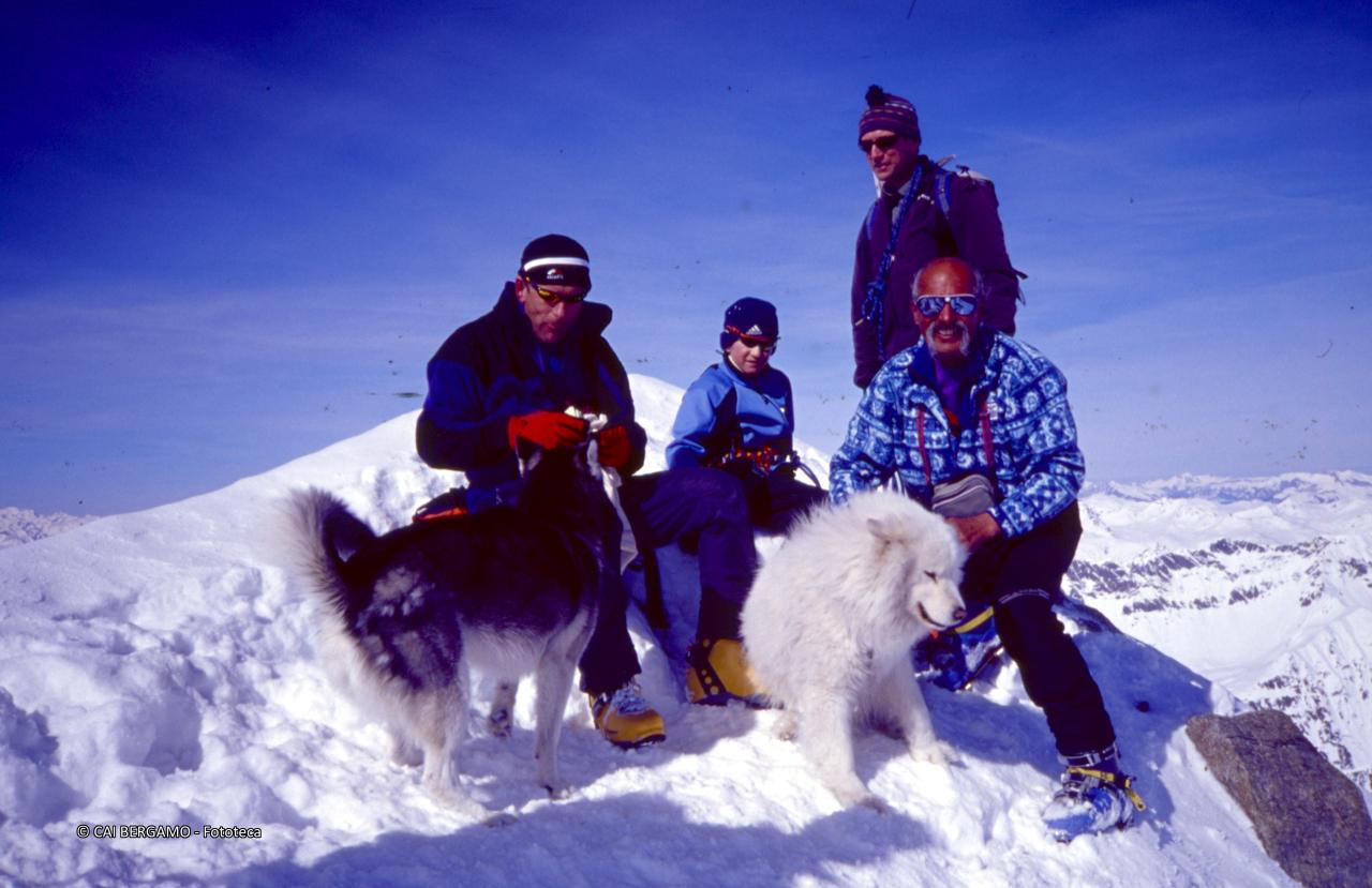 Foto ricordo di Pezzotta con altri scialpinisti e cani di compagnia