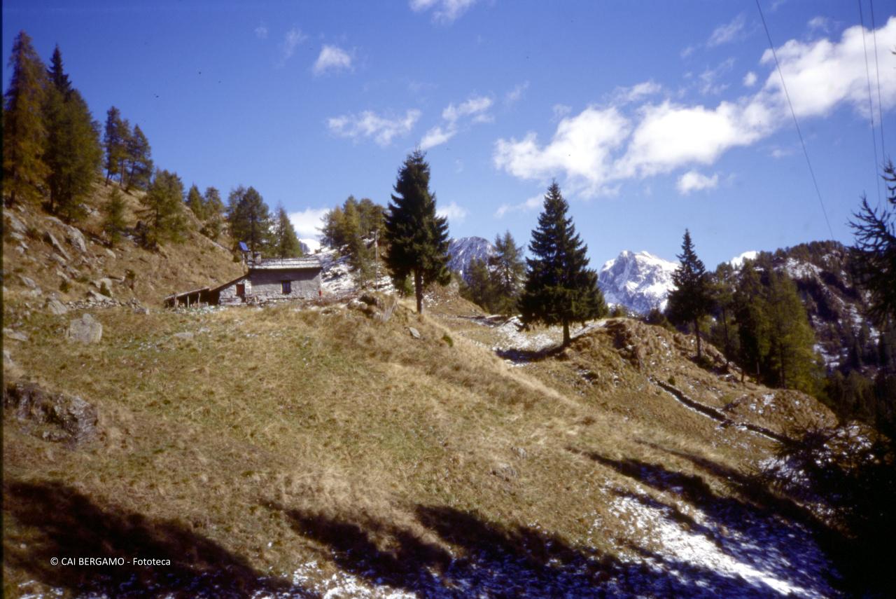Il rifugio Baitone e tra i pini le cime della zona del Calvi