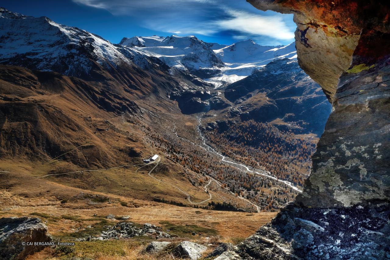 "Dalle rocce al paradiso" - segnalato in "Ambienti montani" - Vista sulla valle con rifugio e cime innevate sullo sfondo